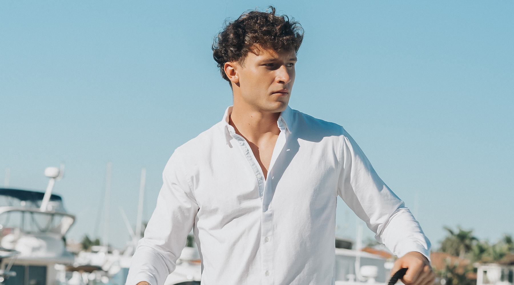 Man wearing Le Club Original swim trunks and linen shirt on boat — holiday gift idea