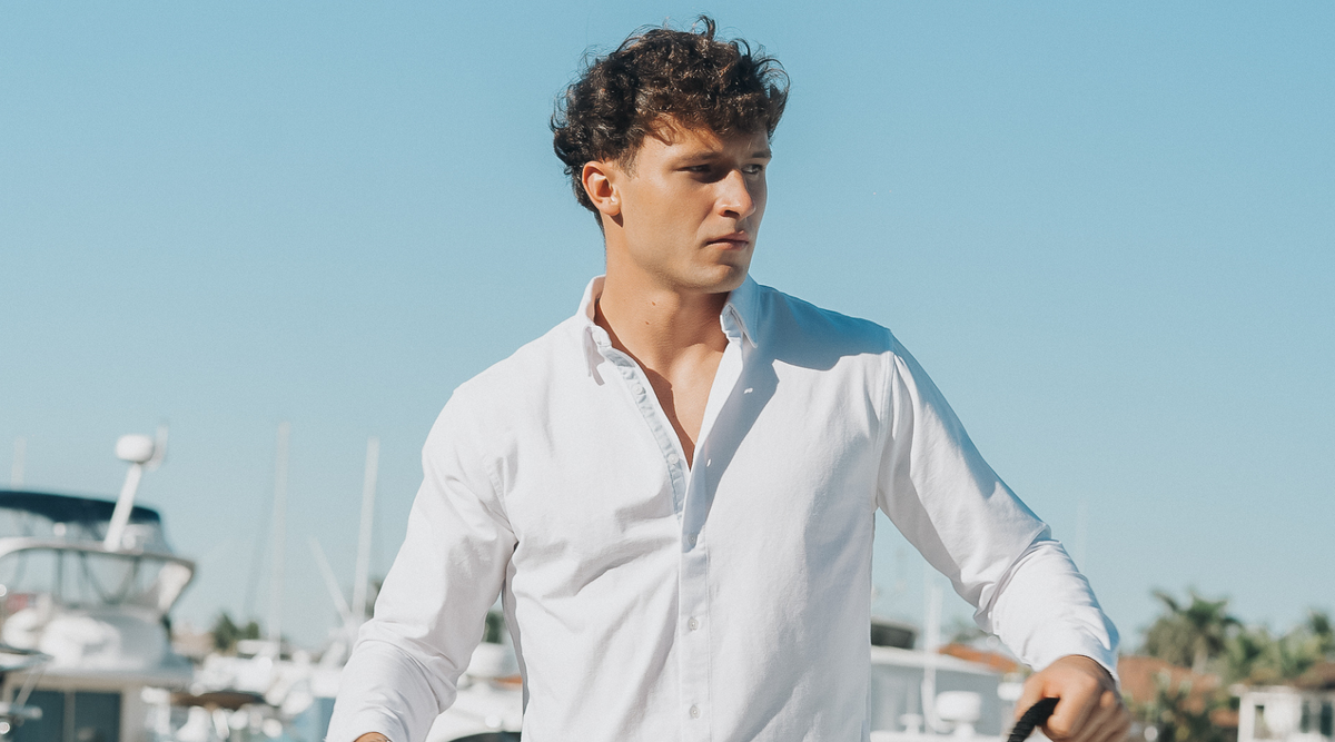 Man wearing Le Club Original swim trunks and linen shirt on boat — holiday gift idea