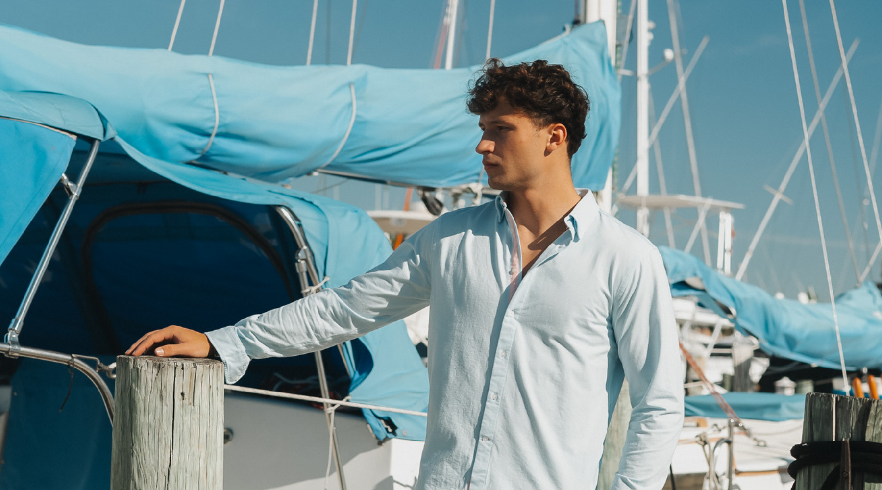 Man wearing Le Club Original swim trunks and linen shirt on boat